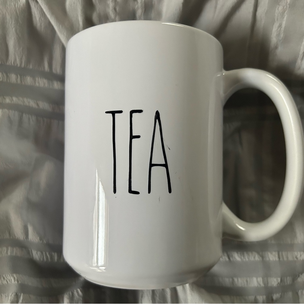 The word TEA printed in black on an all white mug.
